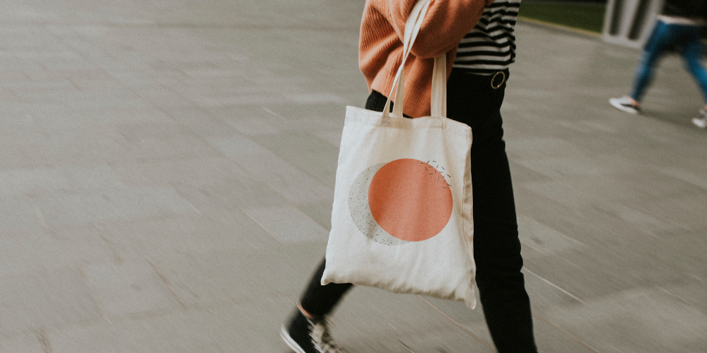 person carrying a branded canvas tote bag